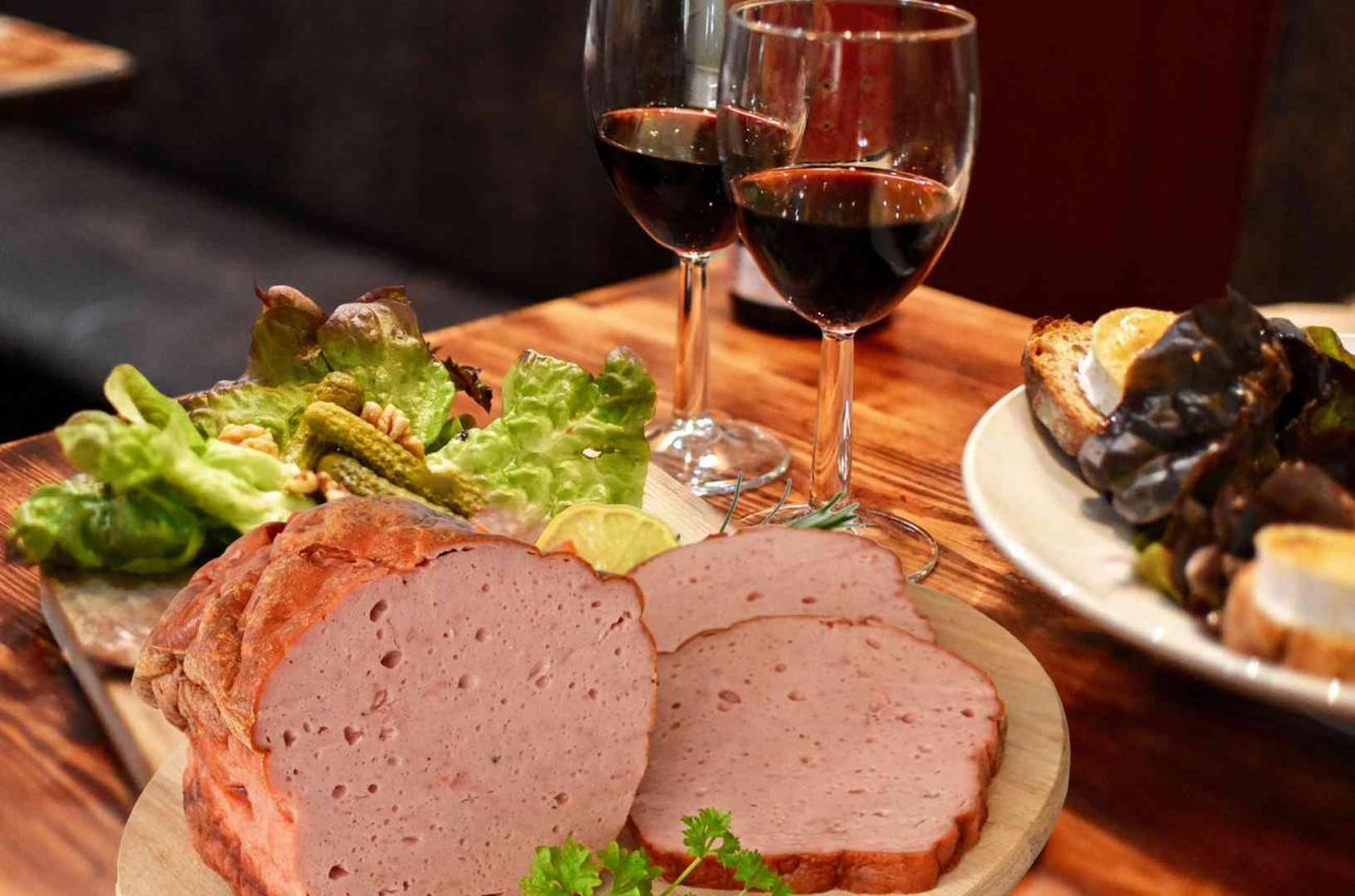 Wein und Läberkäse auf Holztisch mit Salat und Brot angerichtet